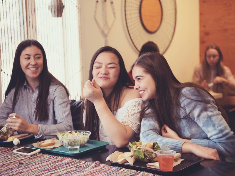 3 young women enjoying lunch in the dining hall